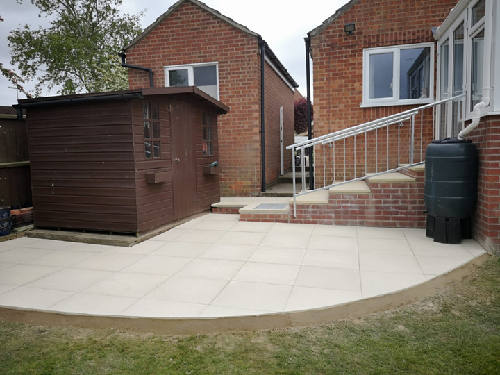 Curved patio area integrated with existing garden buildings