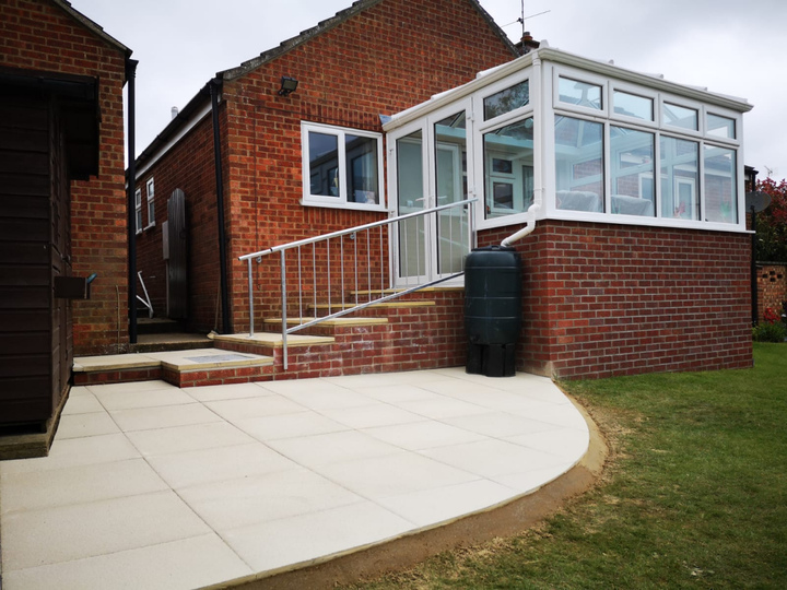 Curved patio area integrated with existing garden buildings